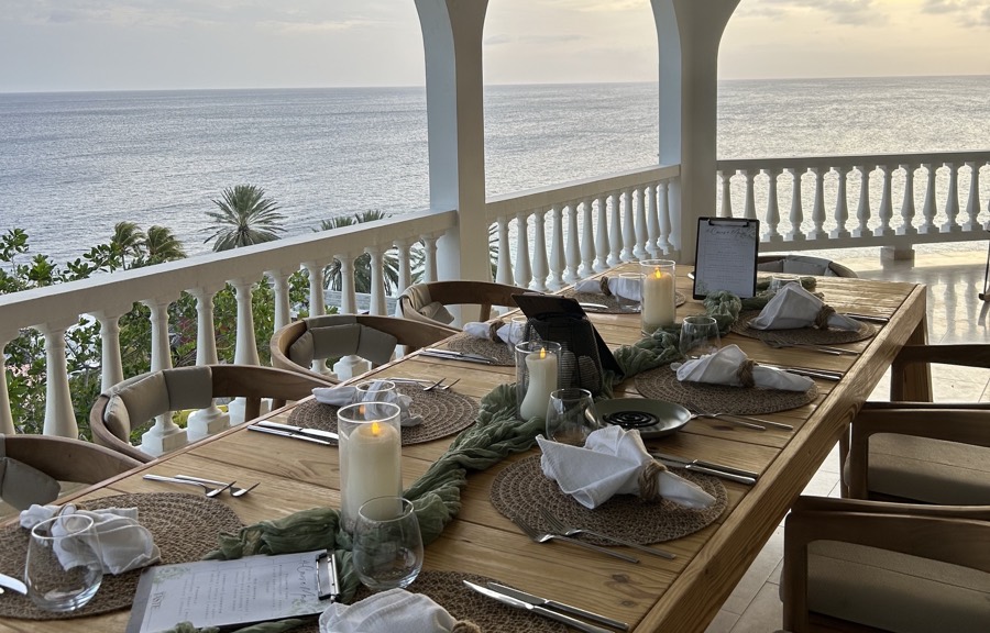 Long table set for a private meal on a veranda with arches and a sea view in Curaçao