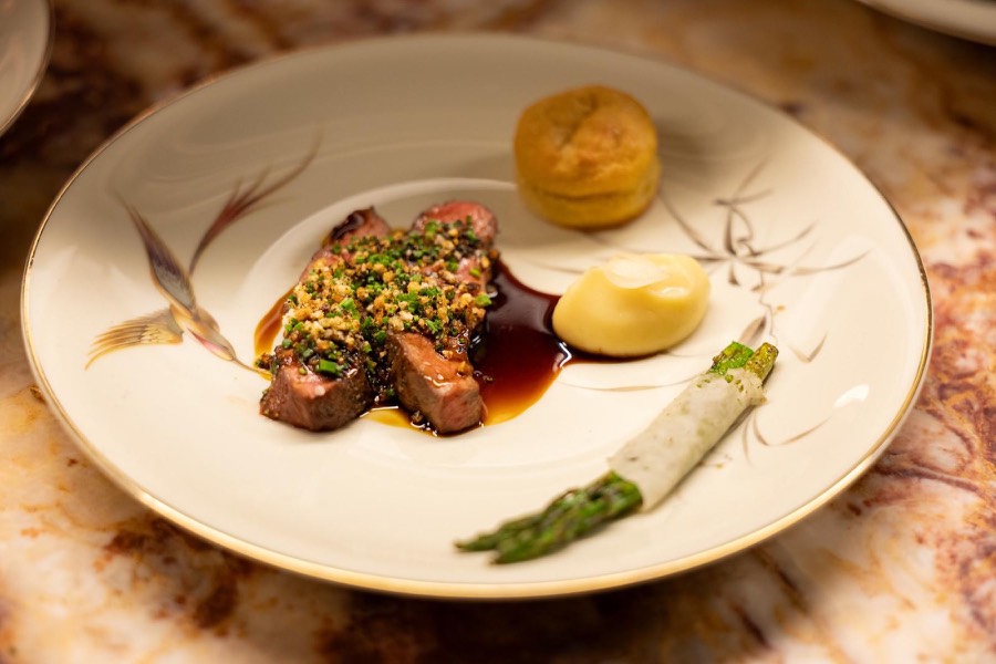 Fine dining main course of sliced beef with asparagus and a rich sauce