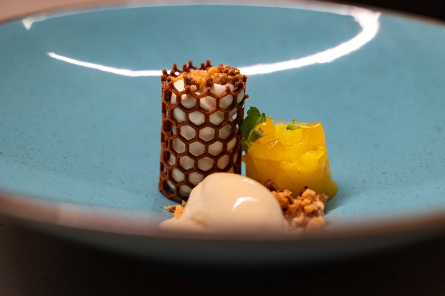 Plated dessert with a honeycomb tuile and ice cream in a turquoise bowl
