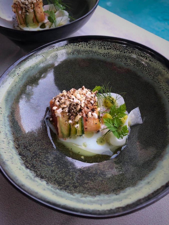 Fine dining starter with fresh herbs on a dark ceramic plate