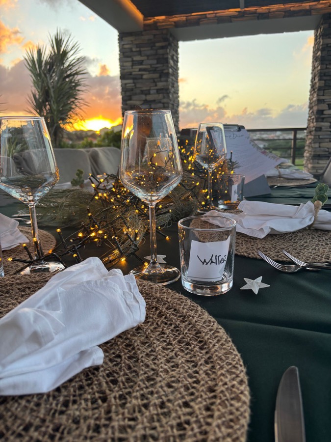 Festive table with string lights and wine glasses on a terrace at sunset